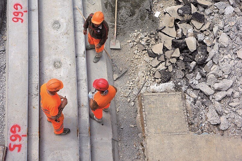 drei Bauarbeiter in orangefarbener Kleidung auf der Baustelle