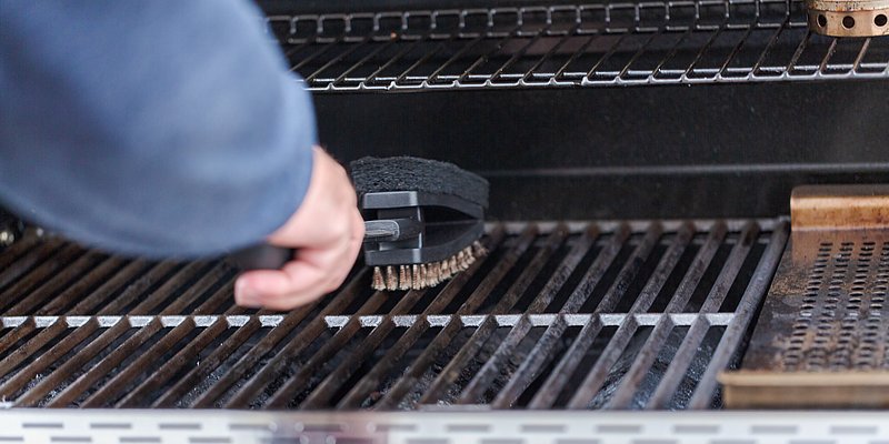 Nahaufnahme von der Reinigung vom Gasgrill mit Bürste