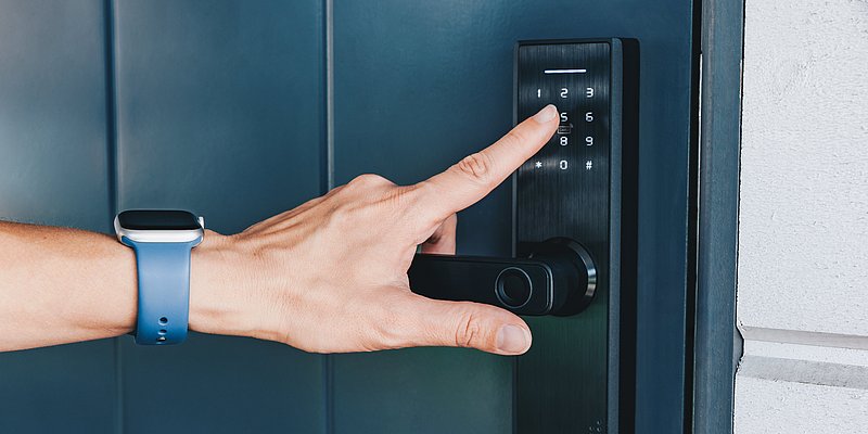 Hand einer Person beim Öffnen einer Tür mit Zahlenschloss