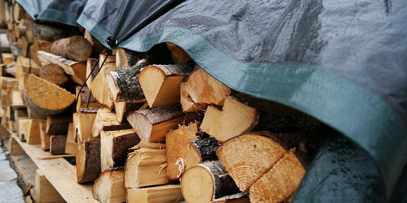 Brennholz lagert draußen zugedeckt