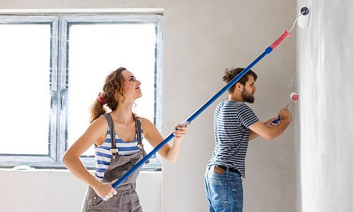 Ein junges Paar malt ein Zimmer gemeinsam aus