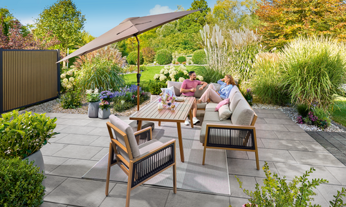 Zwei Personen sitzen an einem sonnigen Tag im Garten auf der Terrasse und unterhalten sich