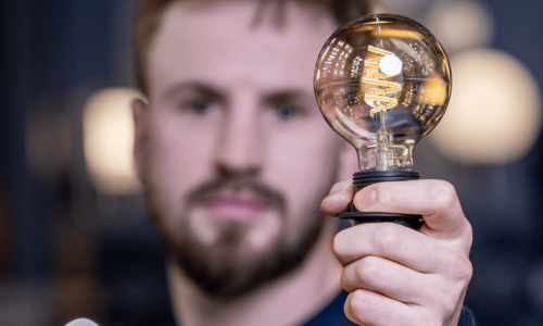 Mann hält leuchtende Lampe in linker Hand