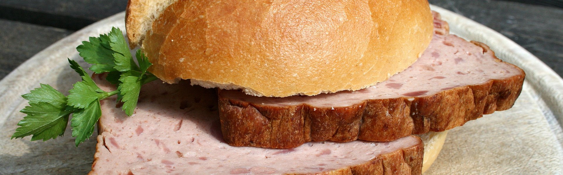 Semmel mit Leberkäse auf einem Holzbrett