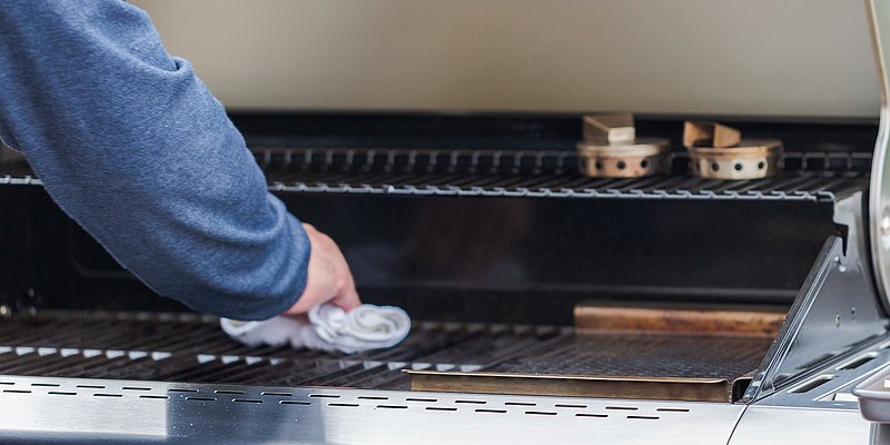 Nahaufnahme von der Reinigung vom Gasgrill mit Putztuch
