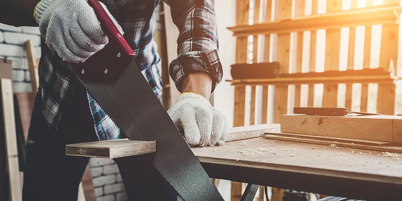 Handwerker sägt mit Händsäge Fuchsschwanz Holz ab