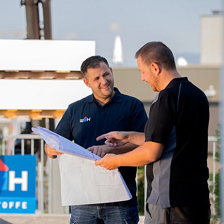Außendienstmitarbeiter im Gespräch mit einem Kunden über den Bauplan