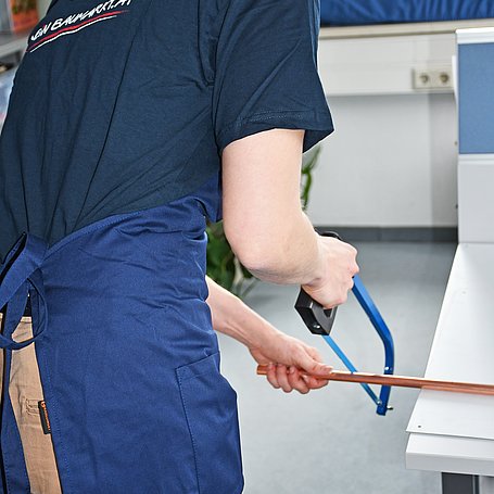 Person am Zersägen eines Kupferrohrs