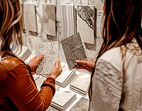 Zwei Personen, welche zwei verschiedene Fliesen miteinander vergleichen