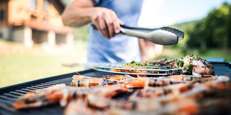 Mit Grillzange Grillgut wenden