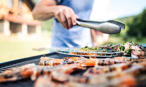 Mit Grillzange Grillgut wenden
