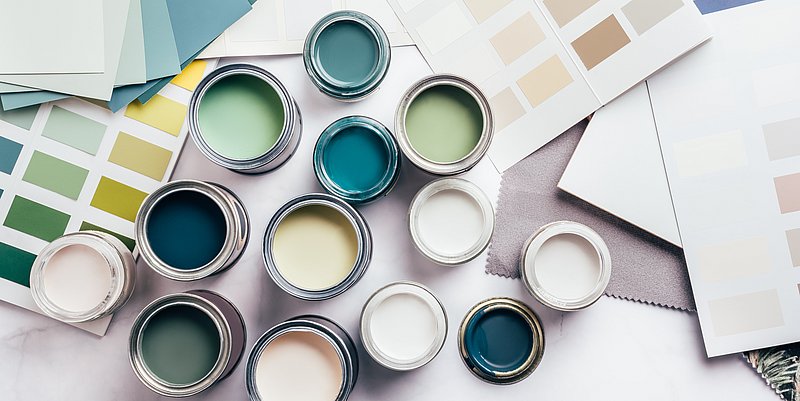 Geöffnete Farbdosen in verschiedenen Farben mit beiliegenden Farbkarten