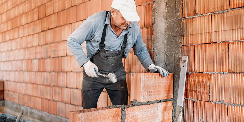 Handwerker zieht eine Ziegelmauer hoch