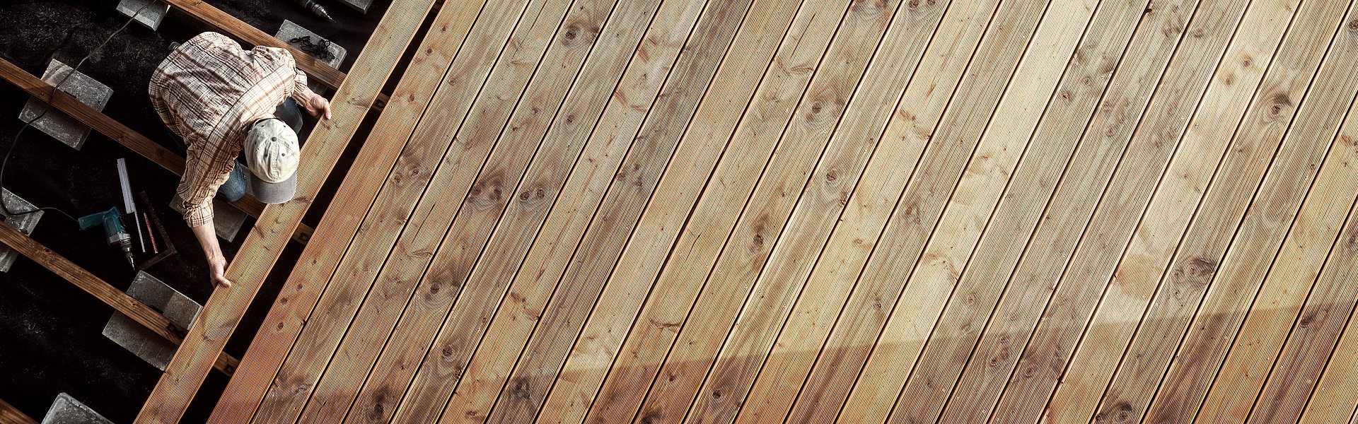 Person beim Verlegen von Holzdielen aus der Vogelperspektive