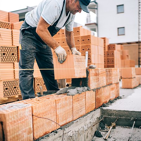 Bauarbeiter beim Errichten einer Hauswand aus Ziegel