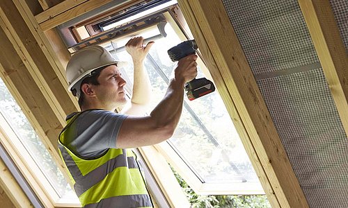 Arbeiter mit Helm, gelber Warnweste und Bohrmaschine