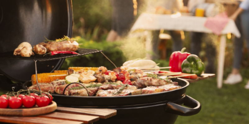 Esstisch mit Personen und ein Grill stehen im Garten