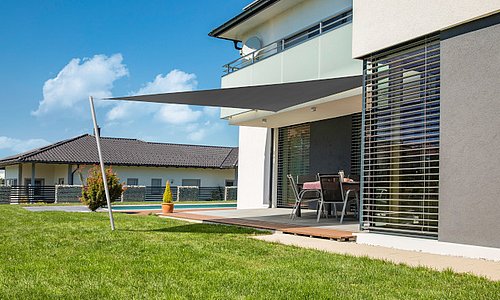 Graues Dreieck-Sonnensegel von Windhager als moderne Terrassenbeschattung