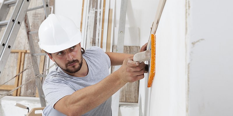 Mann beim Glätten seiner verputzten Wand