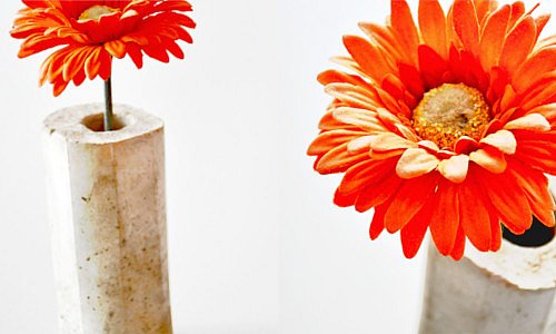 Betonvase mit oranger Blume