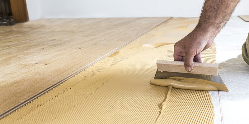 Handwerker beim Verkleben eines Parkett-Bodens