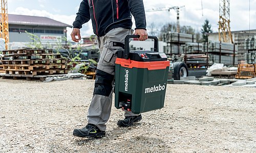 Baustellenarbeiter trägt metabo Kühlbox auf Baustelle