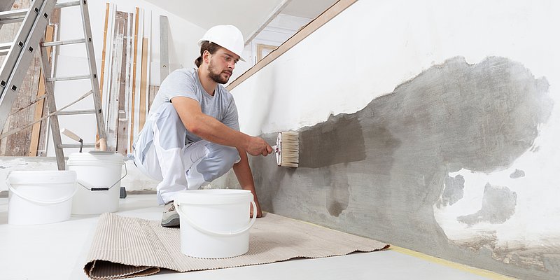 Mann beim Auftragen von Primer auf seiner Wand