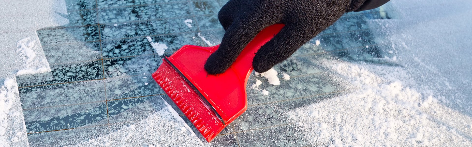 Eiskratzer auf zugefrorener Autoscheibe