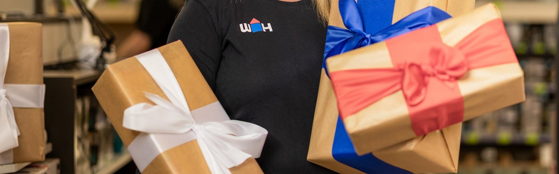 WH Mitarbeiterin hält Geschenk in der Hand weitere befinden sich im Einkaufswagen vor ihr