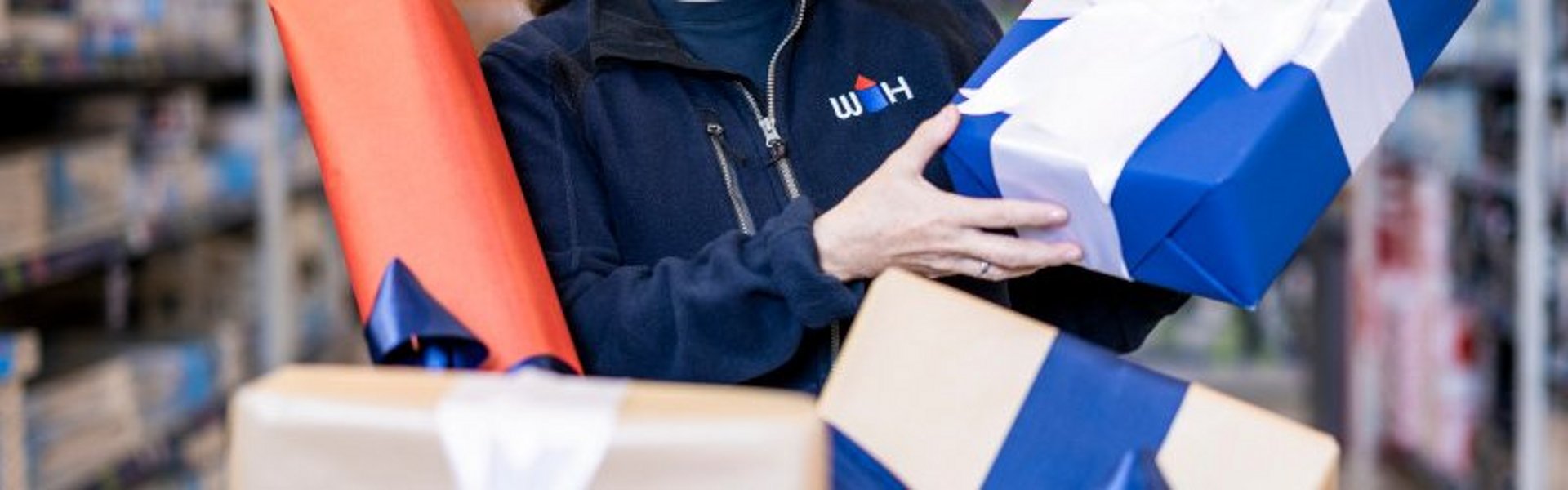 WH Mitarbeiterin hält Geschenk in der Hand weitere befinden sich im Einkaufswagen vor ihr