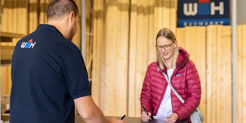 WH-Mitarbeiter berät Kundin in der Holzabteilung