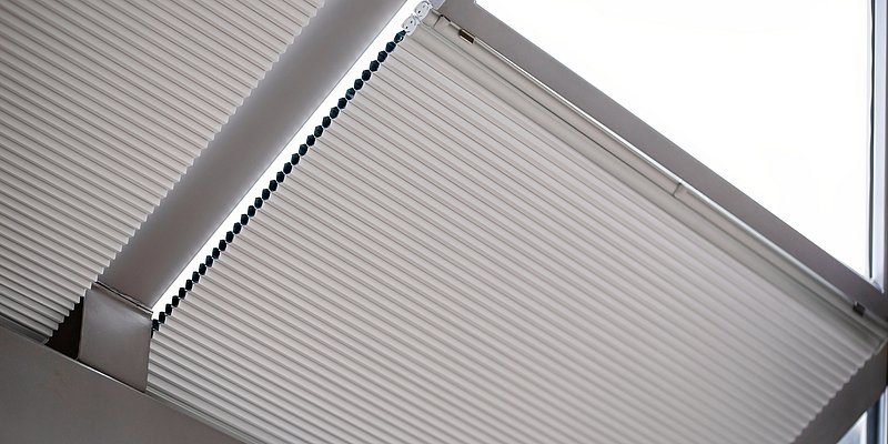 Motorisierte Plissees montiert an einem Dachfenster halboffen